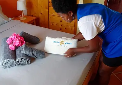 a woman is putting a pillow on a table at Villa Atum. Stella Maris Exclusive in Vila do Maio